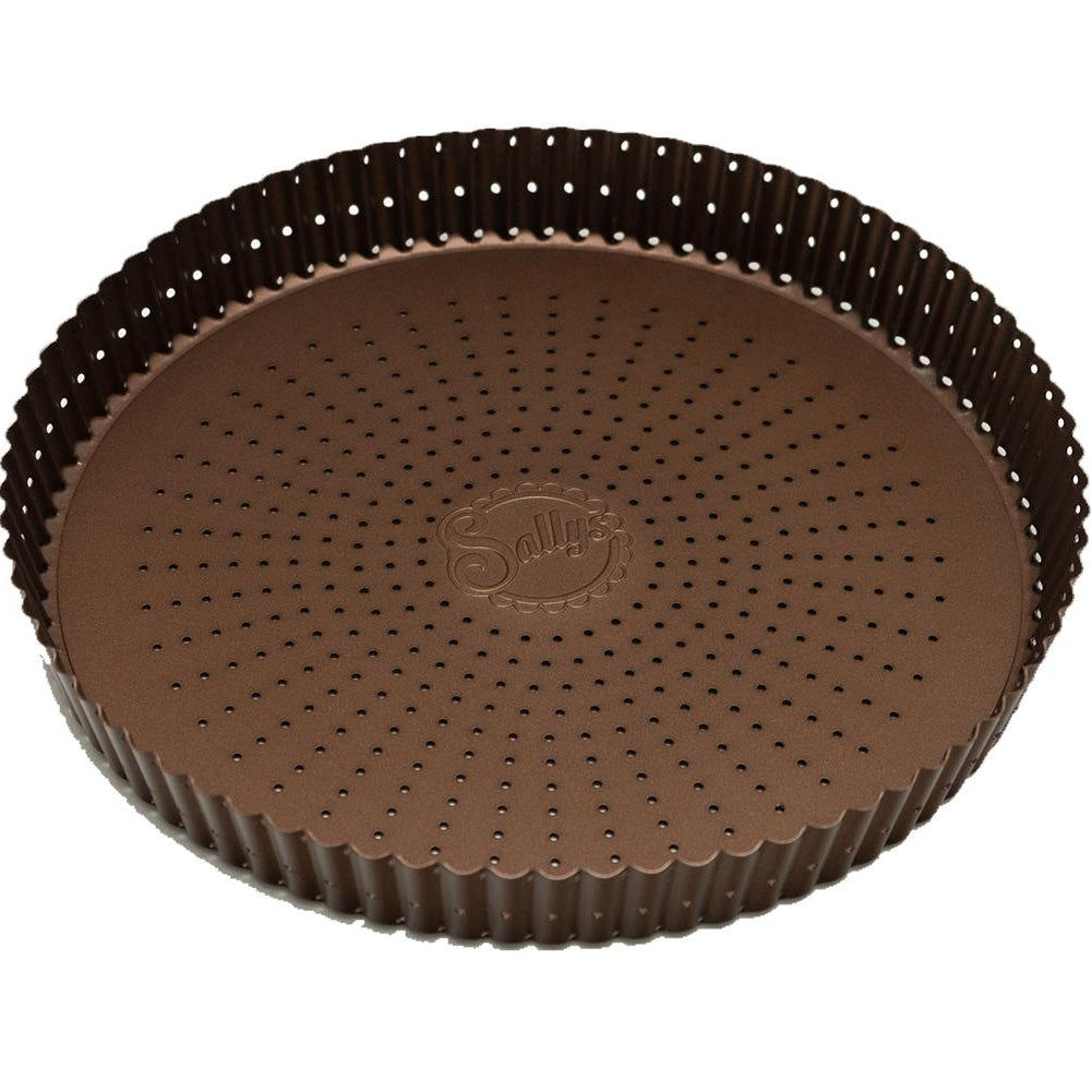 Eine kupferfarbene Tarteform mit perforiertem Boden