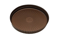 Eine kupferfarbene Tarteform mit perforiertem Boden
