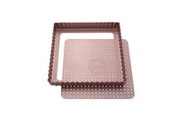 Eine rosefarbene, quadratische Tarteform mit perforiertem Hebeboden