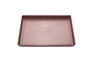 Eine rosefarbene, rechteckige Tarteform mit perforiertem Hebeboden